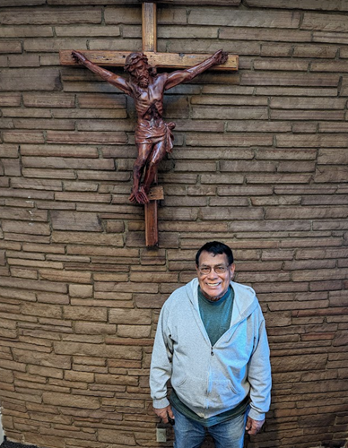 Larry Pacheco stands in front of Cross in Parish Office